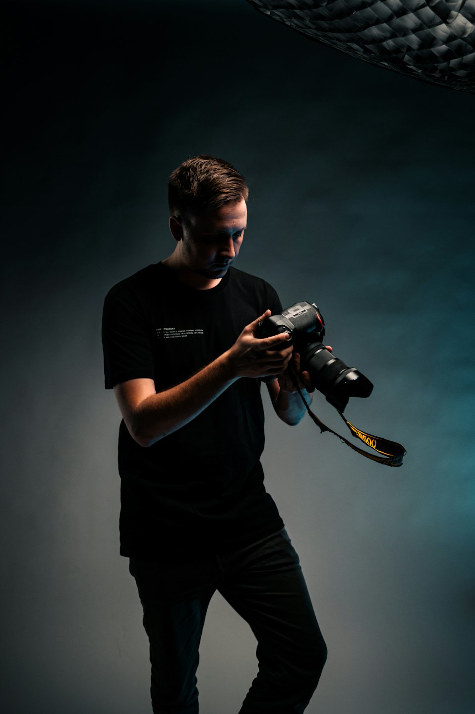 Fotograf justerar kamera med lång teleobjektiv i studio.